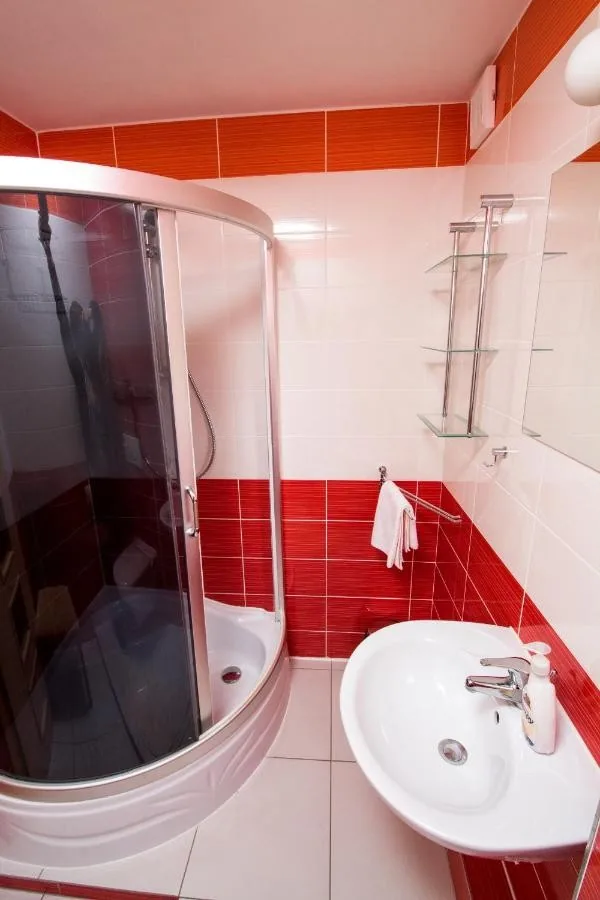 Kúpeľňa so sprchovým kútom a červeno-bielym obkladom